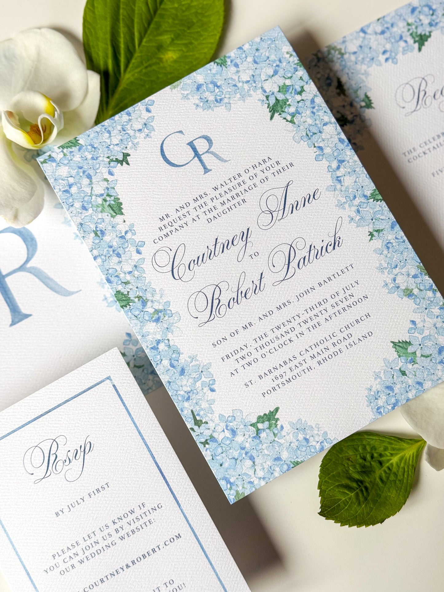 Blue floral watercolor wedding invitation with script names and CR monogram in blue