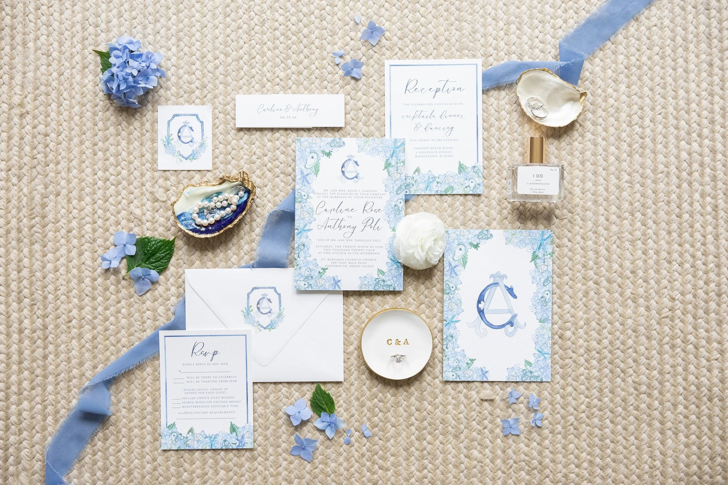 Set of blue and white stationery items on a textured surface with flowers and ribbons.