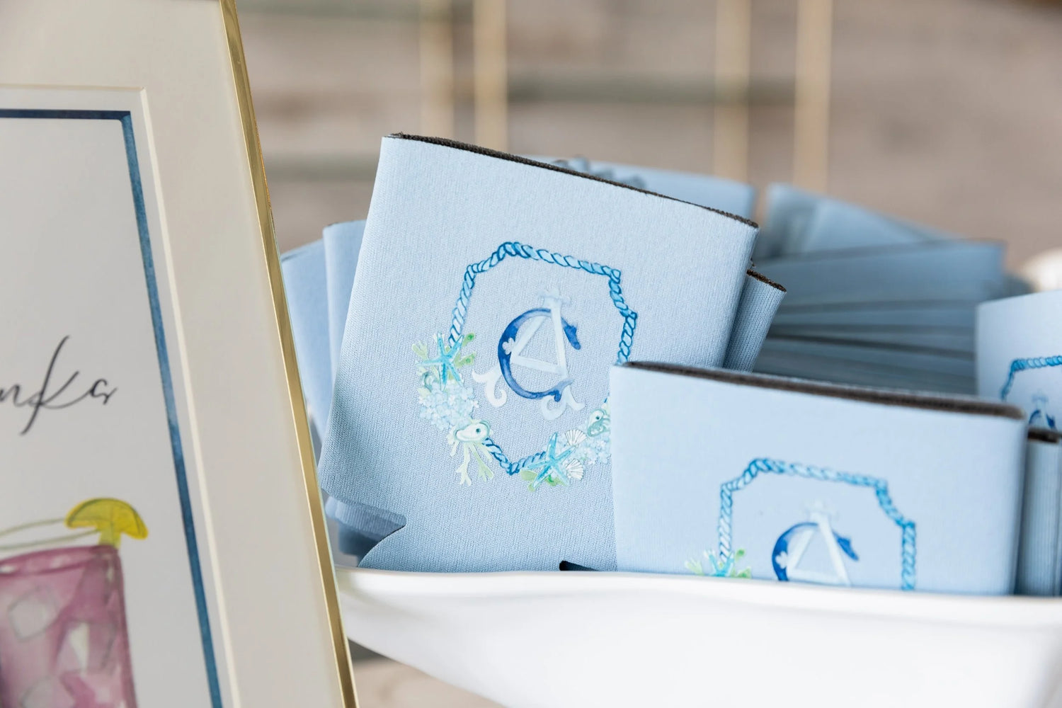 Stack of custom drink koozies with a handpainted monogram crest with an ocean theme.