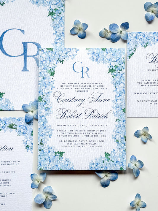 Watercolor wedding invitation with blue monogram CR, floral border, and names