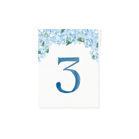 Table number 3 in ocean blue with blue floral border and greenery arch
