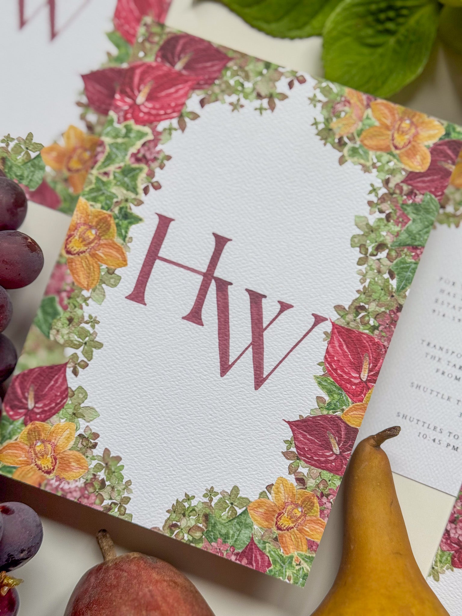 Floral watercolor wedding invitation corner view with large burgundy HW monogram