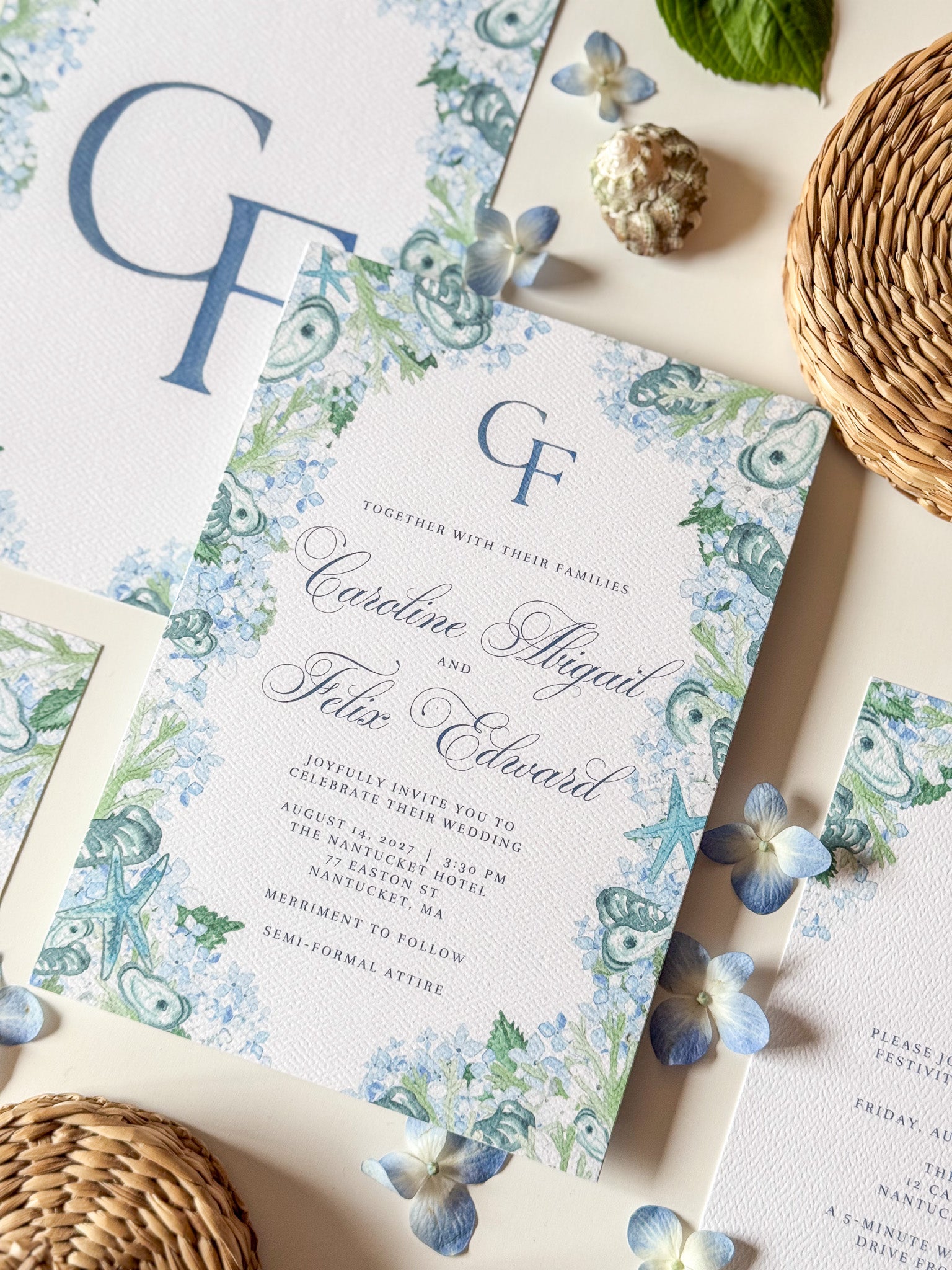 Close-up of wedding invitation front with blue monogram GF, floral watercolor border, and names