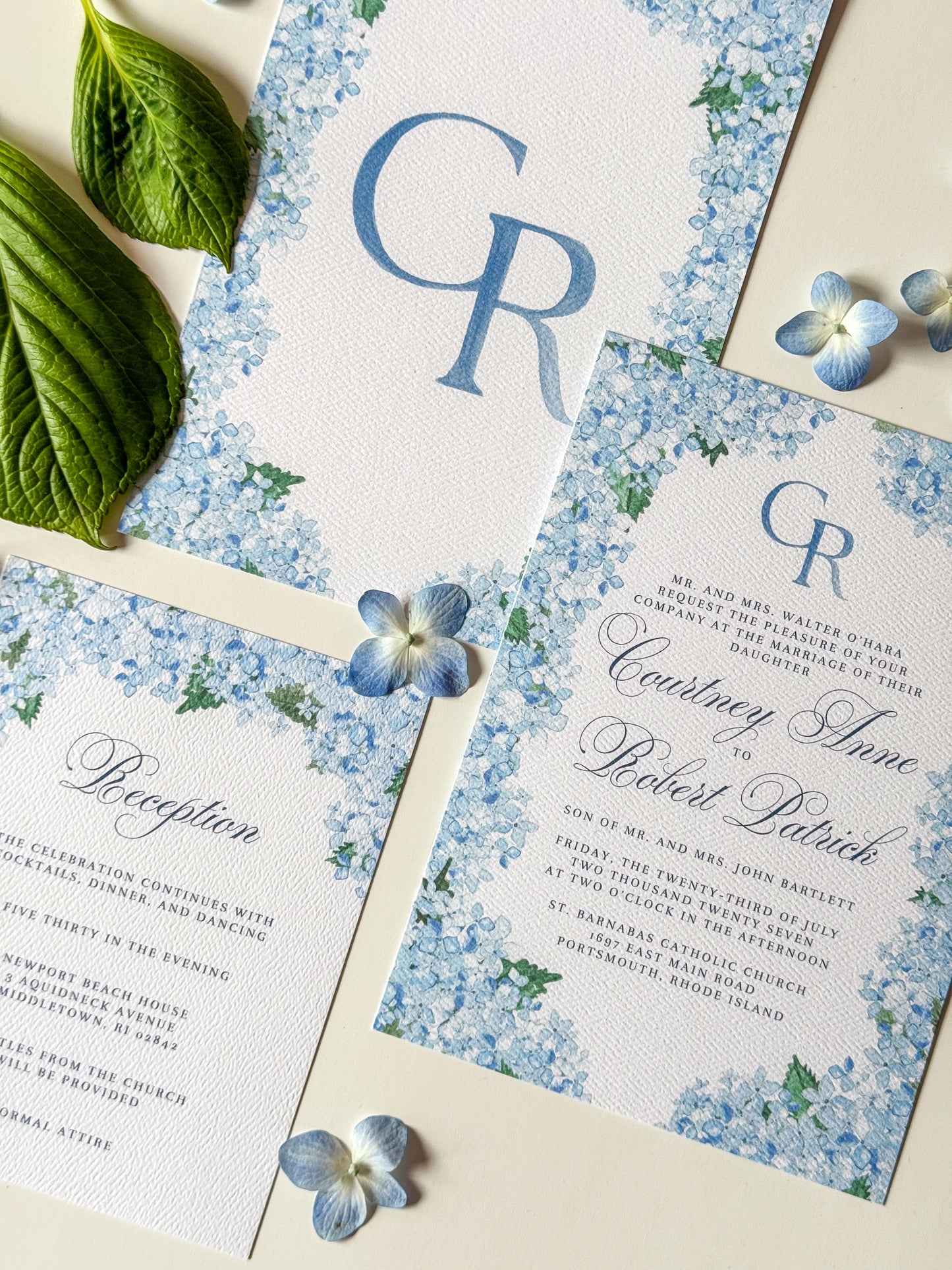 Watercolor wedding invitation with blue floral corners and CR monogram on the center card