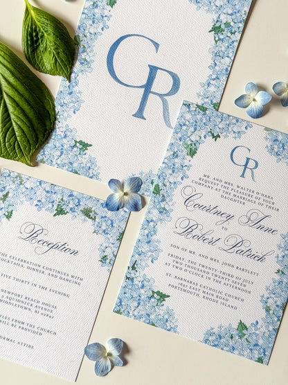 Watercolor wedding invitation with blue floral corners and CR monogram on the center card