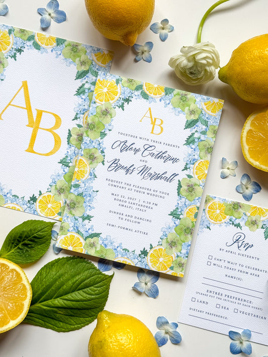 Watercolor wedding invitation with lemon and blue floral border, monogram “A” and “B”.
