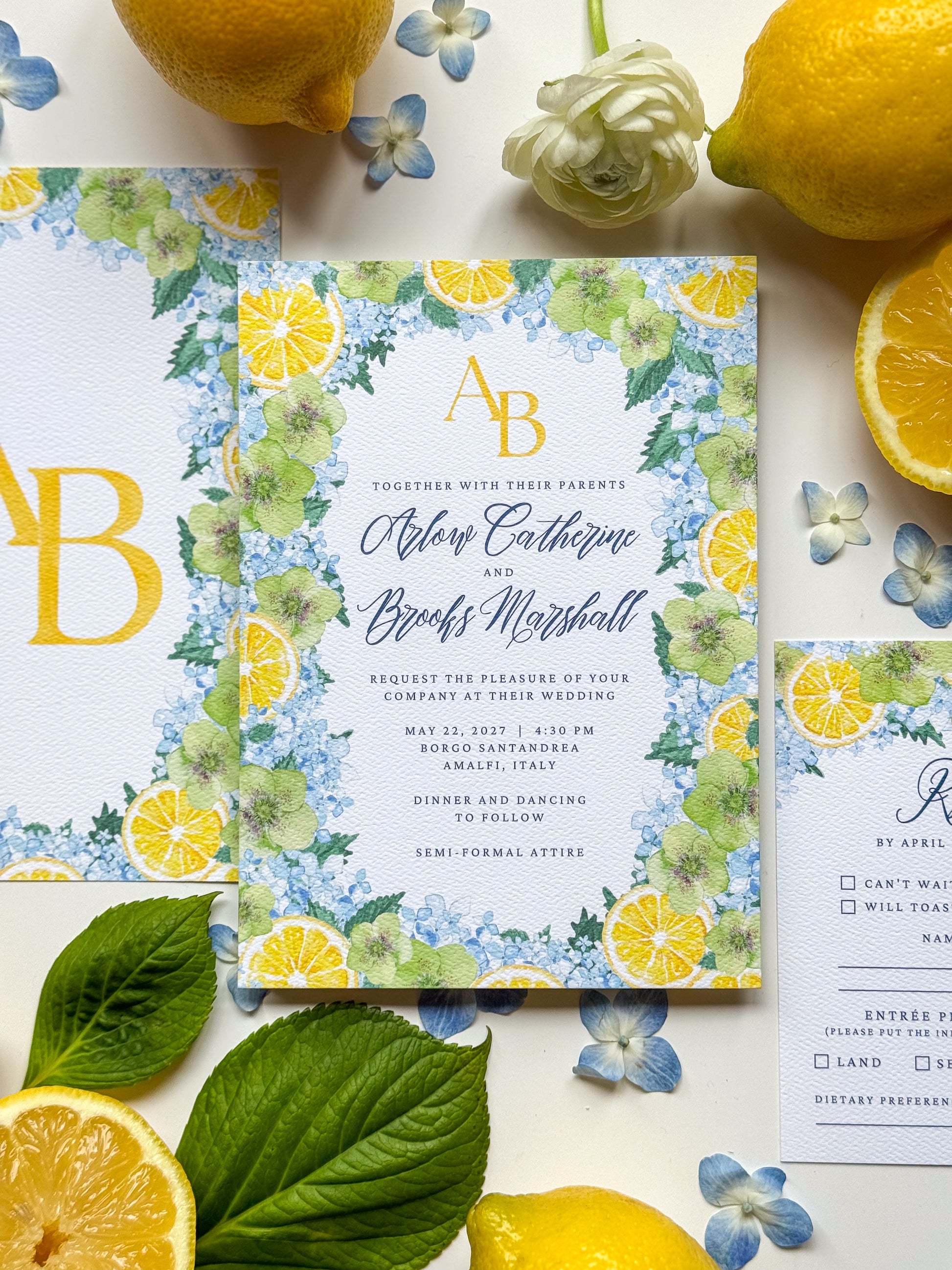 Watercolor wedding invitation with lemon and blue floral border, gold initials AB